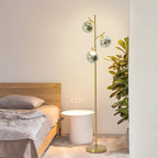 Ambris floor lamp beside a bed, smoke-gray molten glass globes
