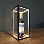 Welion LED wireframe table lamp glowing around a wine bottle, used as a lit display case on a console table