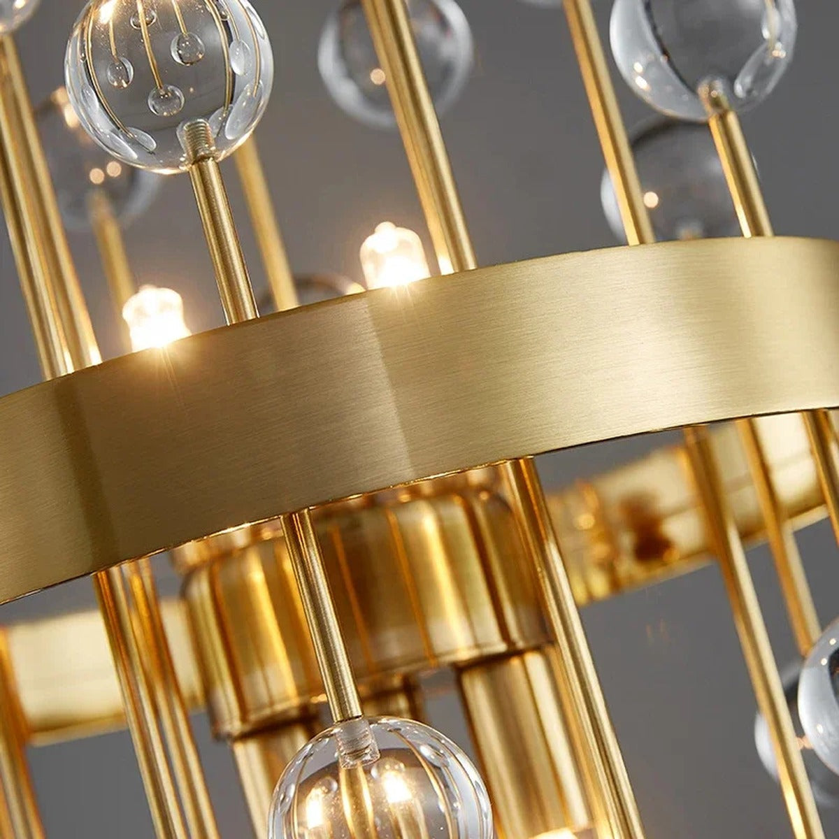 Close-up of Morvena Clear Sphere Crystal glass orbs and brushed brass rods, lit