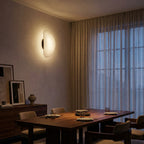 Tenzora organic textured wall sconce lifestyle view over a dining table, warm white light