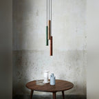 Nvaelion terrazzo tube pendants above a weathered stone wall, staggered heights