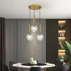 Modern Glass Globe Pendant Light Hovrix - Cascading Trio, Gold & Clear Glass, over a dining table