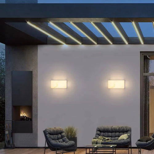 Avrexon outdoor sconce — warm amber glow through alabaster stone at night