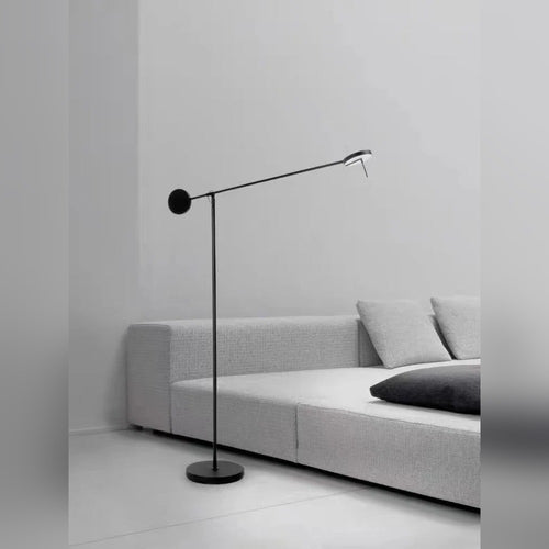 Bilancio floor lamp beside a sofa, arm angled toward the seating