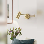 Arqventa brushed gold swing-arm wall sconce with fresh flowers on a side table