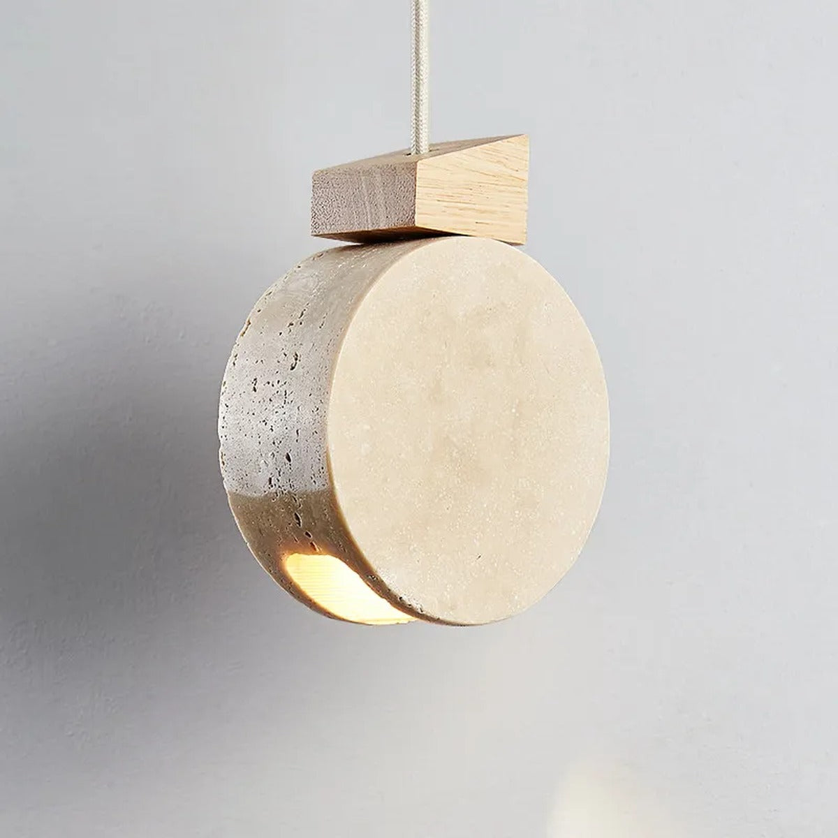 Marevaux travertine stone disc pendant light, lit, hanging view