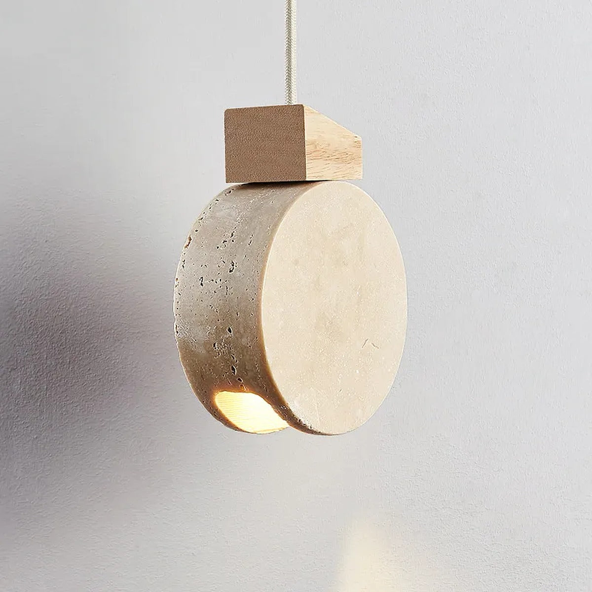 Marevaux travertine disc pendant, close-up angle showing warm edge-lit glow