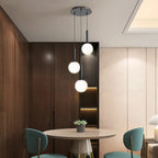 Modern Glass Globe Pendant Light Hovrix - Cascading Trio, Black & Frosted Glass, over a dining table