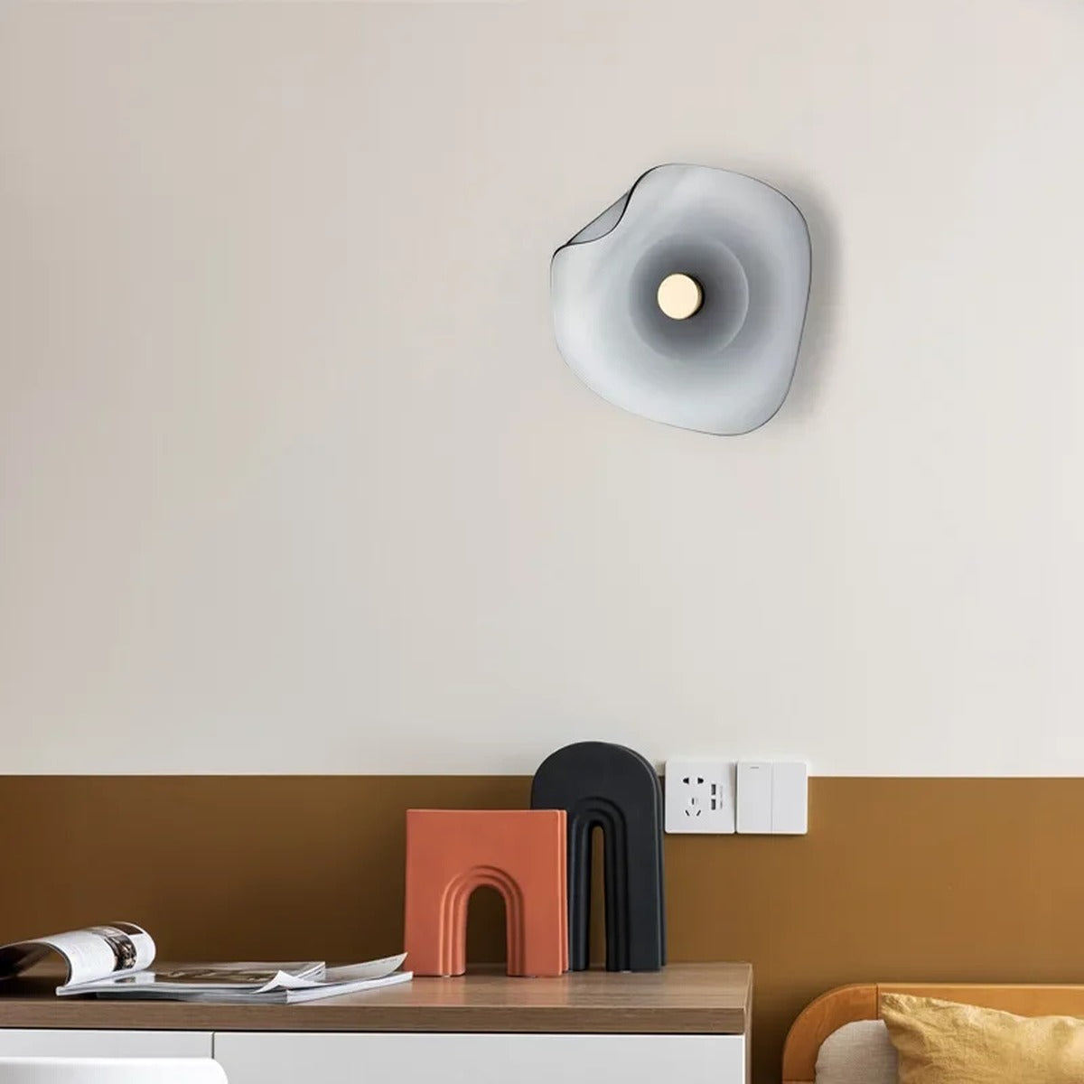 Devoria wall sconce in smoky grey mounted above a console table in a warm-toned living space