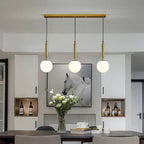 Modern Glass Globe Pendant Light Hovrix - Linear Trio, Gold & Frosted Glass, over a dining table