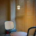 Orbivex pendant — lit view showing soft opal globe glow through dark arc frame