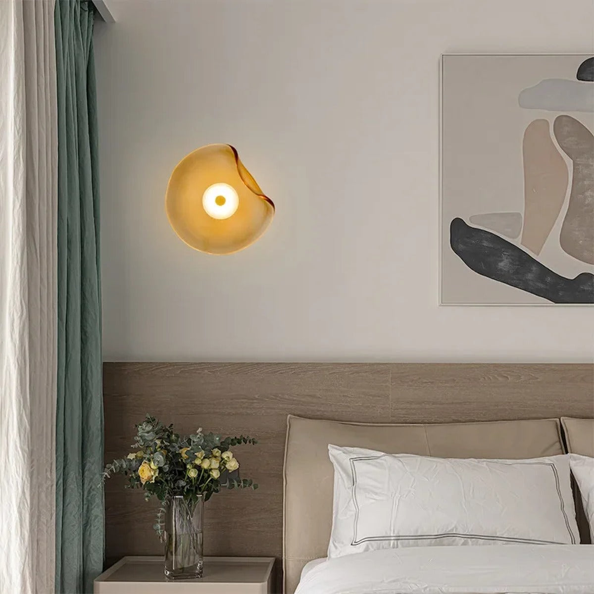 Devoria organic wavy frosted glass wall sconce in amber, glowing warmly beside a bed in a minimalist bedroom