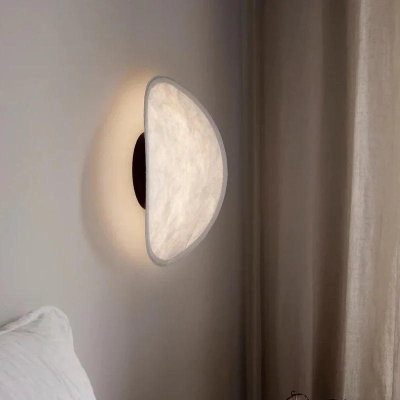Tenzora wall sconce lifestyle view above bedside table, Black backplate, warm white light