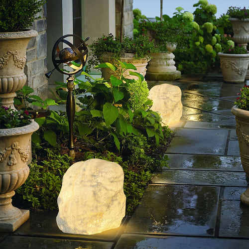 Lumeroc illuminated stone lamps beside potted plants on a garden terrace