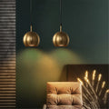 Solindra brass globe pendant light – pair hung above velvet headboard in dark green bedroom