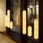 Shizumi paper drum pendant lights in varying heights, illuminated storefront at night