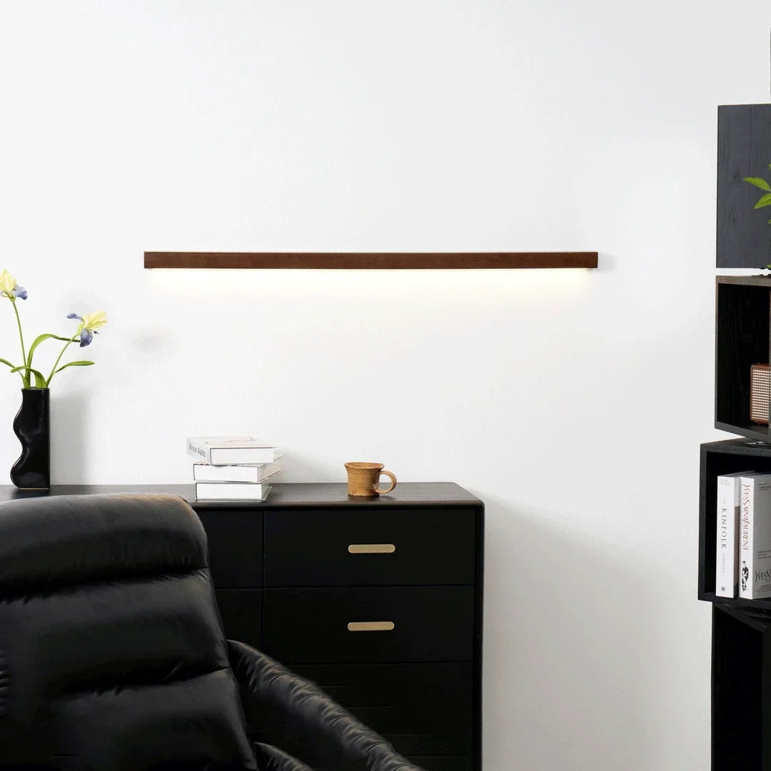 Solvela walnut linear LED wall sconce lit above office cabinet
