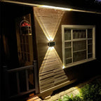 Nexford solar wall light illuminating a stone garden wall