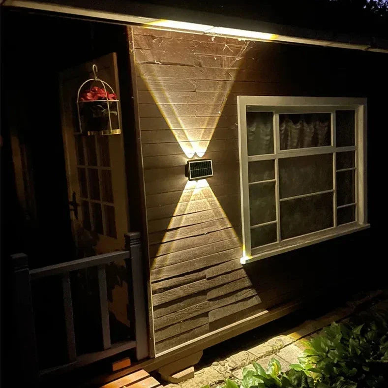 Nexford solar wall light illuminating a stone garden wall