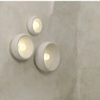 Kalvora plaster wall sconces lit on textured wall