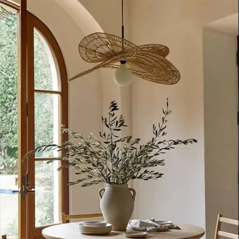 Lotara Lotus twisted rattan pendant above a round dining table with olive branch arrangement