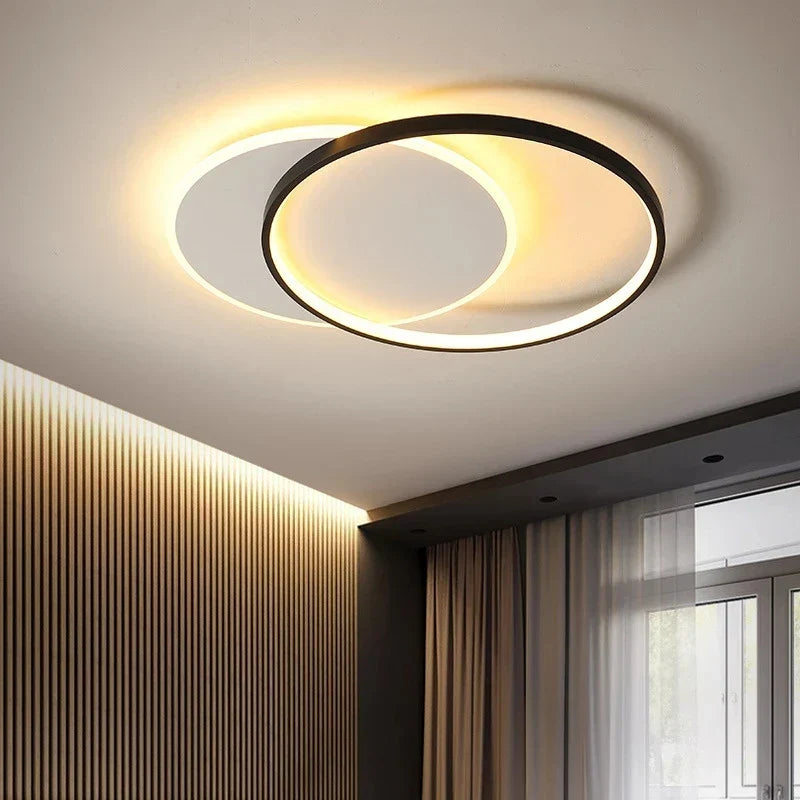 Orvena round ceiling light glowing warm above a bedroom with linen curtains
