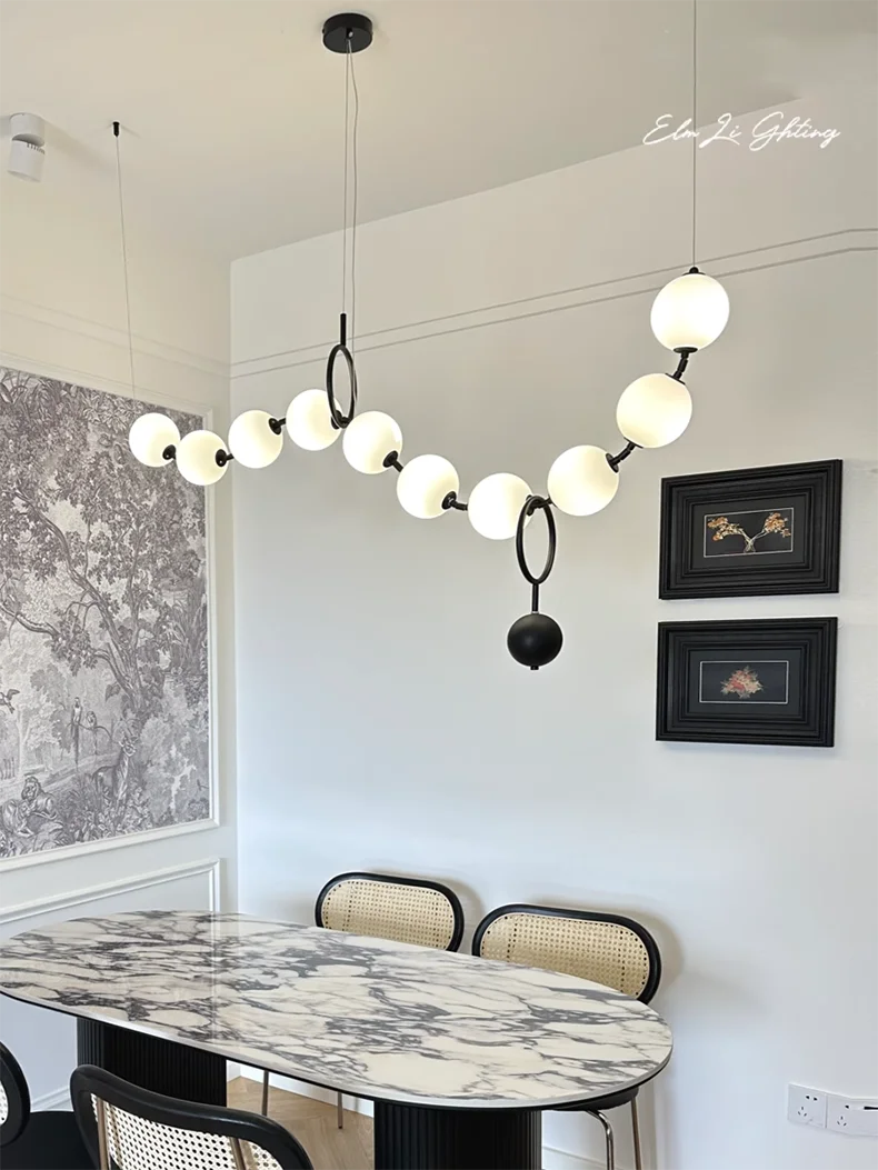 Sculptural Glass Orb Chandelier Ilnox in Matte Black above a dining table