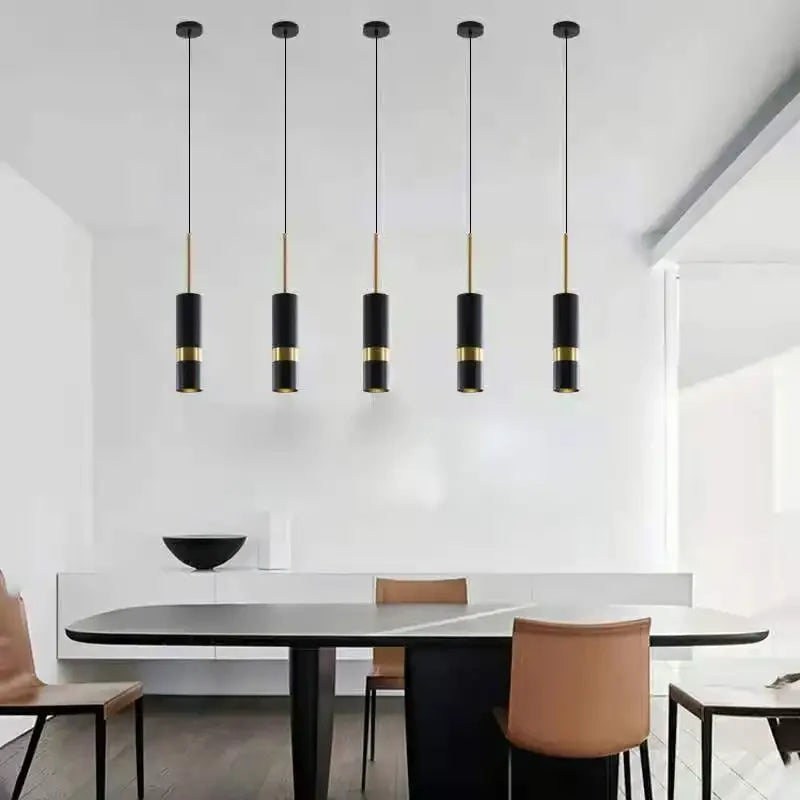 Polanthos angled cylinder spotlight pendants over a dining table, brass and black finish