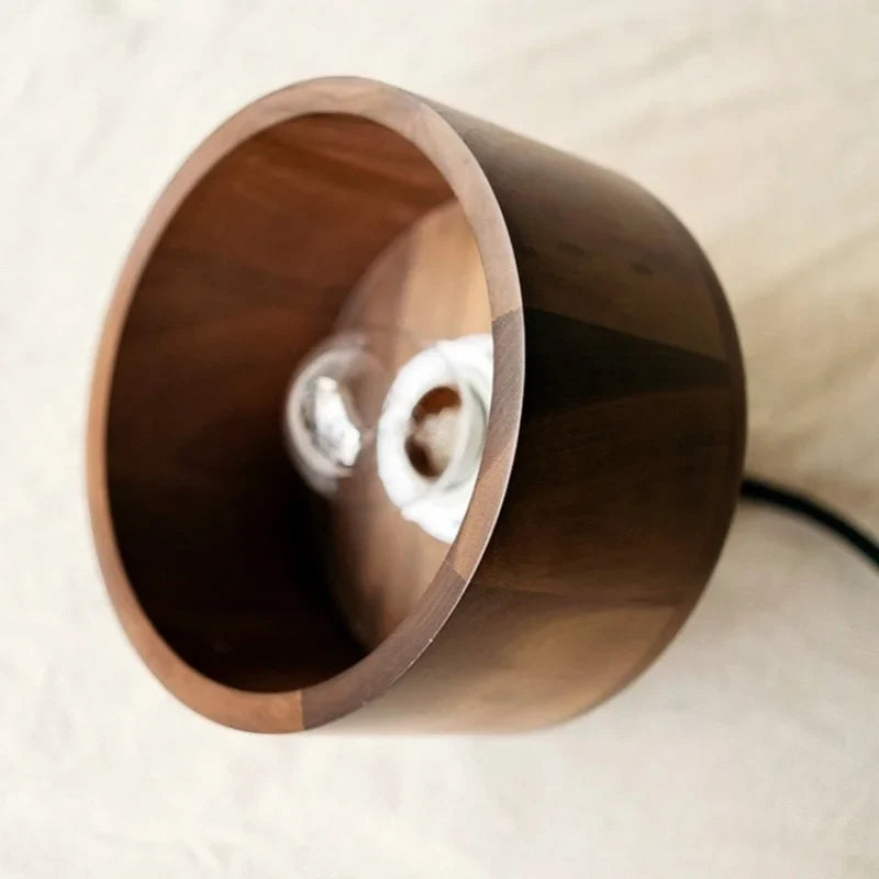 Waelvix walnut and brass pendant lights suspended over a bedside nightstand