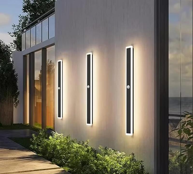 Three Veltora wall lights lit at dusk on a modern coastal facade