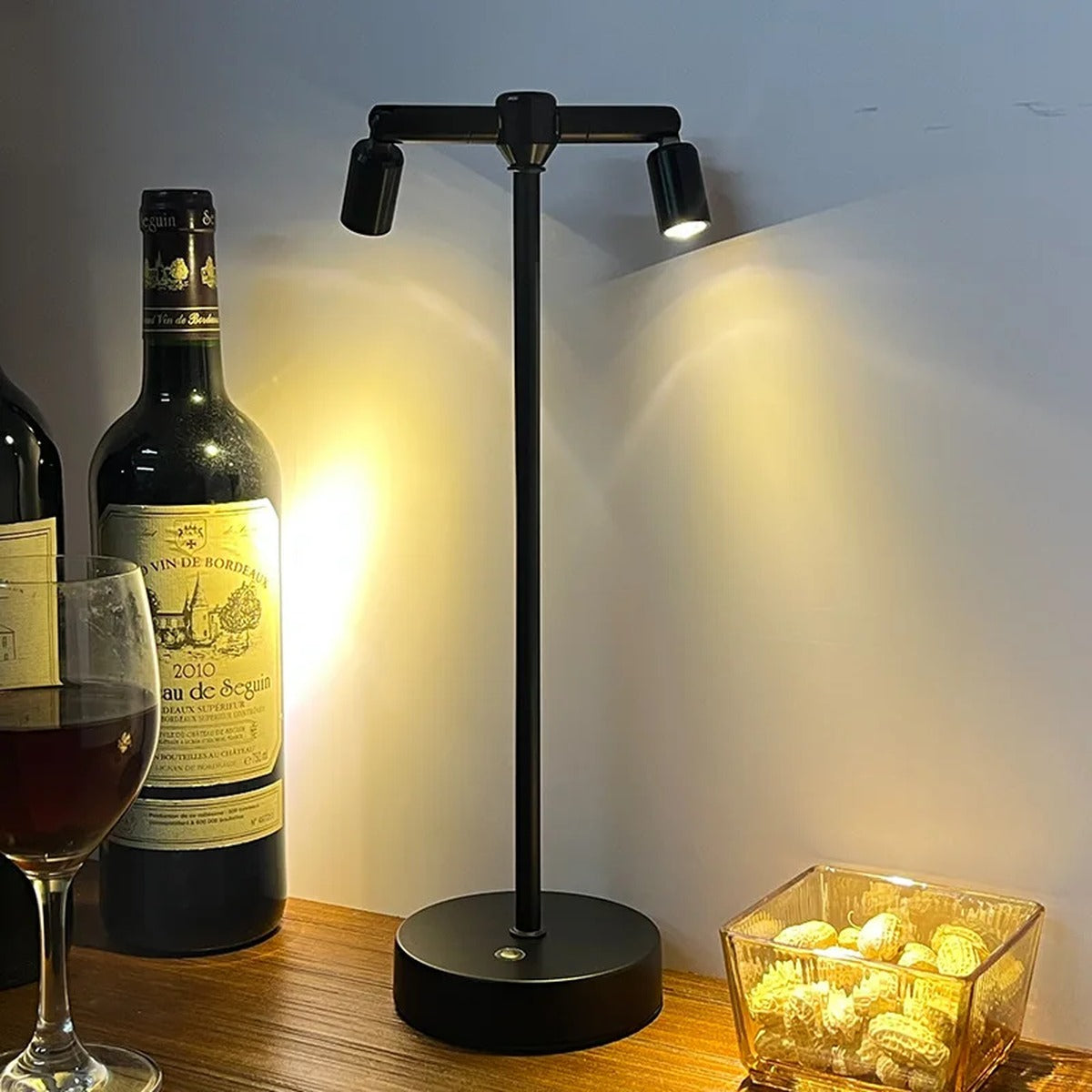 Tarvion rechargeable multi-spotlight LED table lamp — 2-head matte black version on a bar counter beside wine