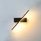 Binova adjustable wall sconce mounted above a home office desk, rotated to 330 degrees, warm ambient light