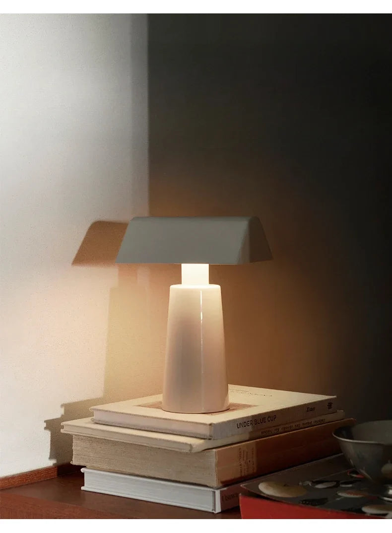 Cordless banker-style table lamp in deep red on a side table