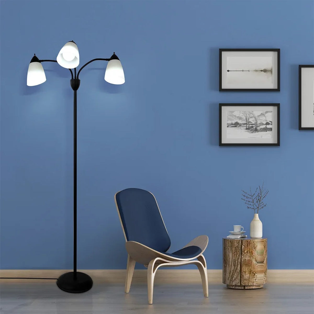 Merelix floor lamp lit with cool white E27 bulbs beside a reading chair