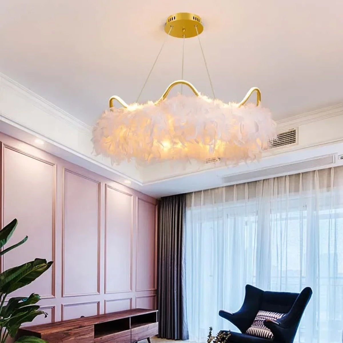 Jevon white feather halo chandelier — large white feather ring with gold crown arms glowing warm in pink-toned living room