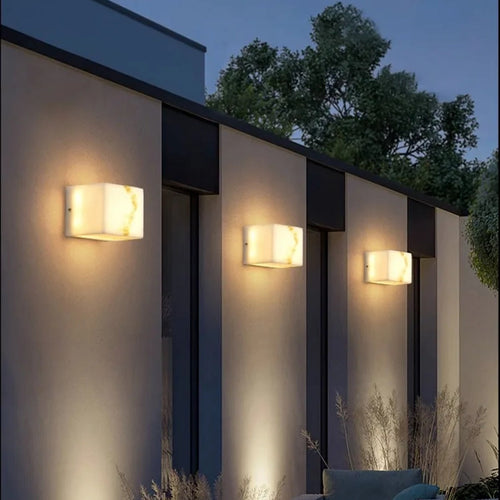 Avrexon alabaster cube outdoor wall sconce — three units on architectural facade at dusk