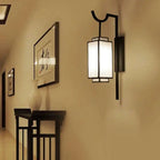 Luxeva lantern wall sconce in matte black illuminating a hallway