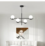 Jorval sculptural glass globe chandelier, 4-head, above a bed in a molded bedroom