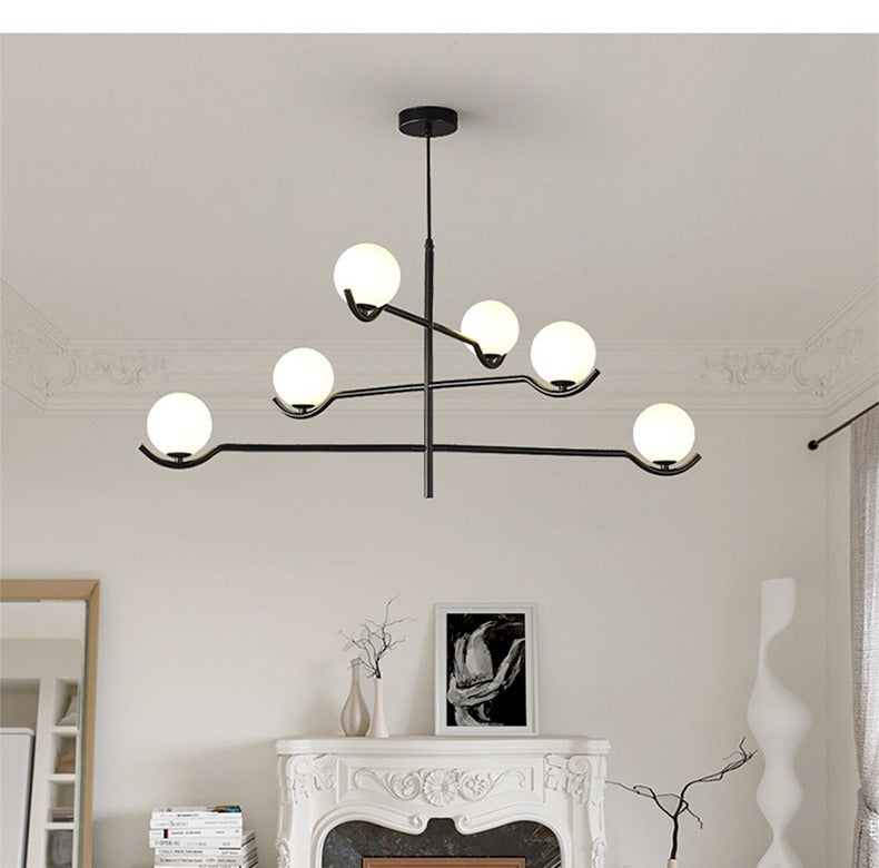 Jorval sculptural glass globe chandelier, 6-head, over a marble fireplace mantel