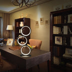 Circolia triple ring LED table lamp in Matte Black on a desk in a furnished study