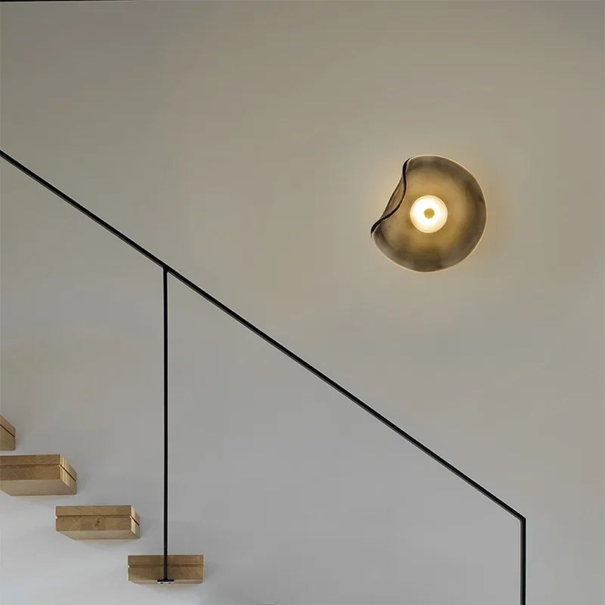 Devoria wall sconce in smoky grey, illuminating a staircase wall with soft ambient light