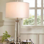 Orindel table lamp beside a window on a bedside table stacked with books
