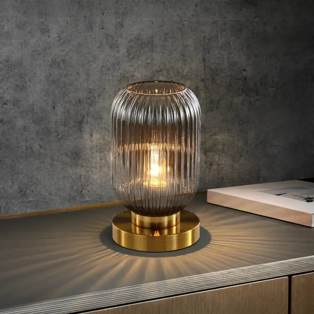 Nervira ribbed glass table lamp Smoked Grey on brushed brass disc base – warm filament glow
