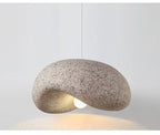 Tempero organic stone-texture dome pendant in dusty pink, glowing warm — studio view